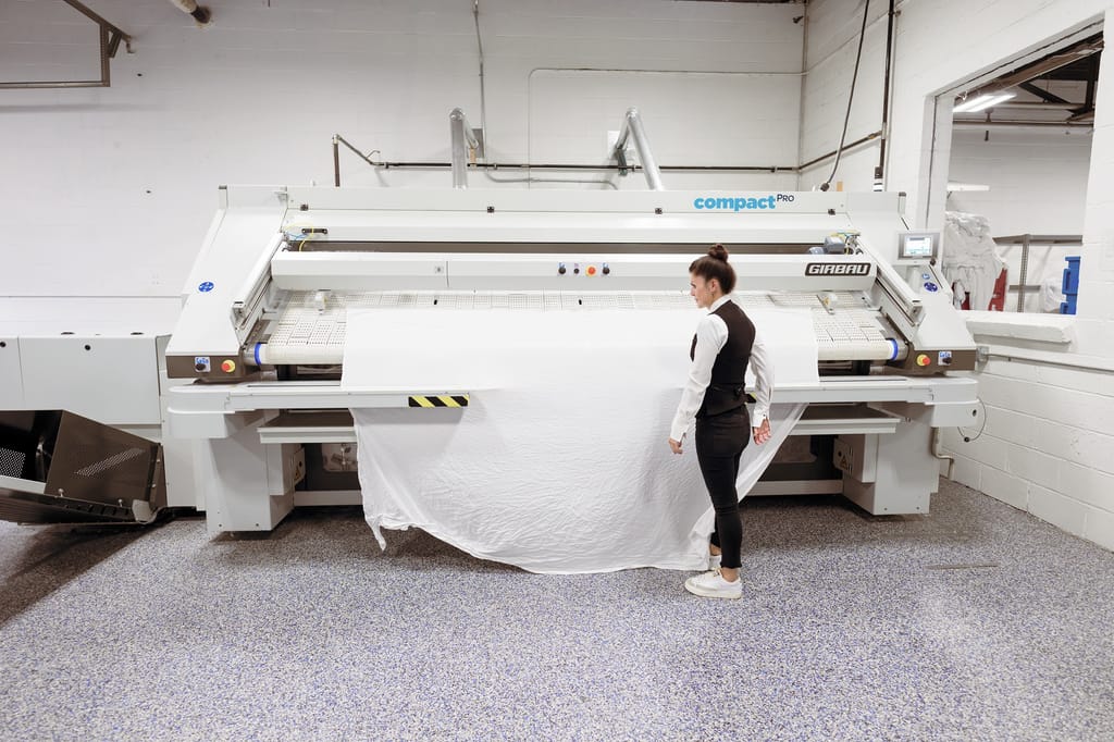Operator processing linens at Blue River Laundry