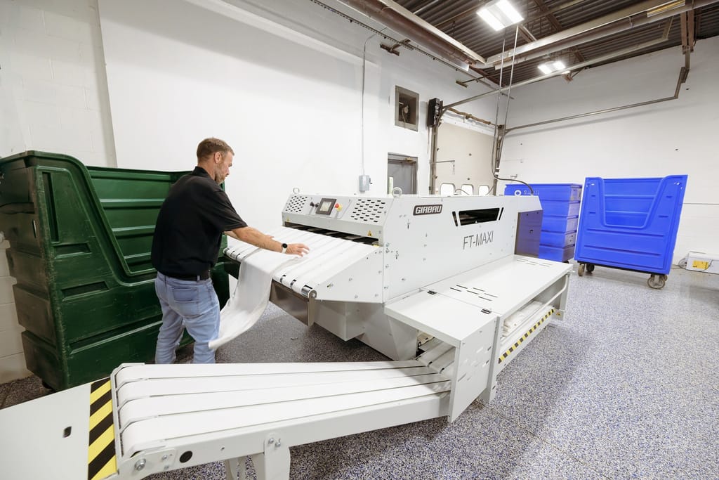 Flatwork ironer processing bed linens at Blue River Laundry